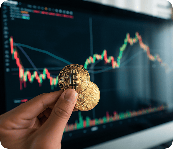 Main tenant deux bitcoins devant graphique