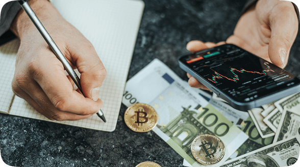 Mains écrivant trading crypto billets et smartphone